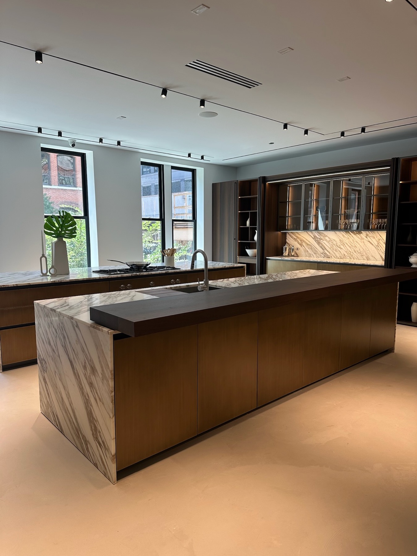 A kitchen island clad in veined marble, with a dark oak counter